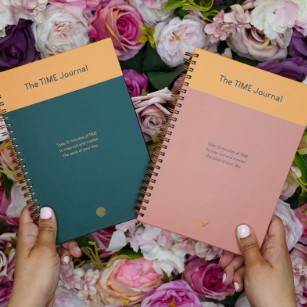Two TIME Journals, green and pink, held over a bed of roses